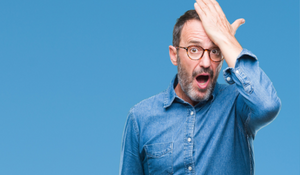 Man in blue shirt with glasses hand on head